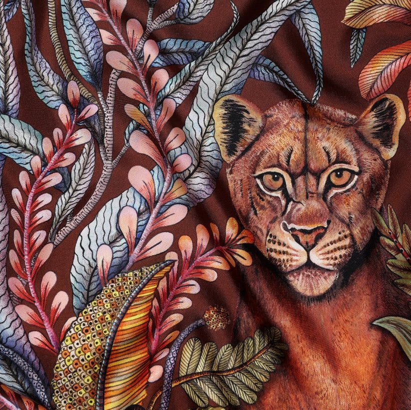 A zoomed-in detail of a lioness’s intense gaze, surrounded by detailed foliage, emphasizing the scarf's artistry and lifelike animal depiction.
