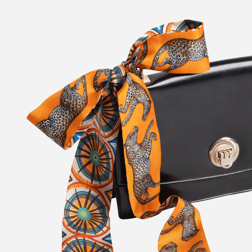 The twill wrapped around the handle of a black luxury handbag, demonstrating its use as an elegant accessory for bags.