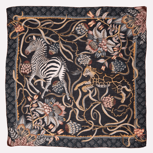 A luxurious wool and modal blend wrap featuring a detailed safari-inspired pattern with zebras, leopards, and botanical elements in a rich, dusk-toned colour palette.