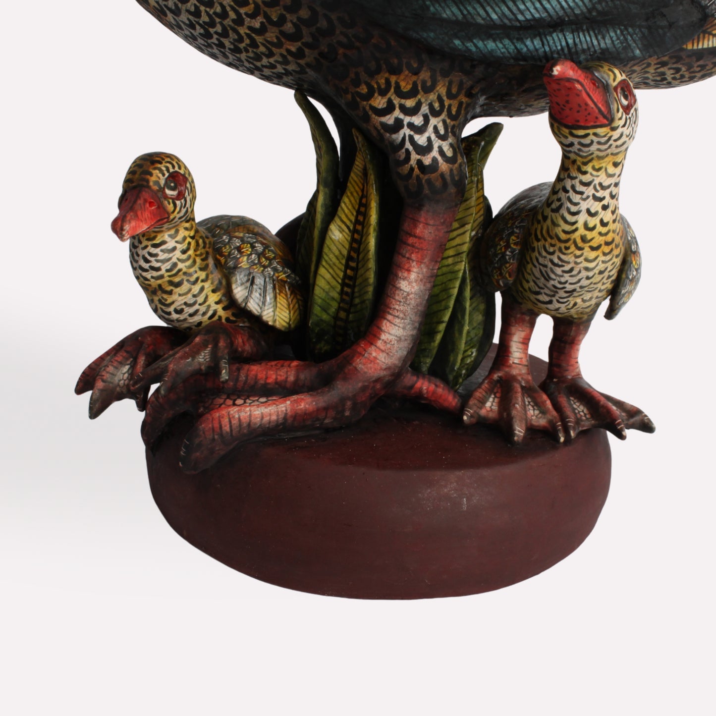 A zoomed-in shot capturing the base of the sculpture, where the goslings are nestled beneath their mother. The detailed expressions and lifelike stance of the figures enhance the emotional connection within the artwork.