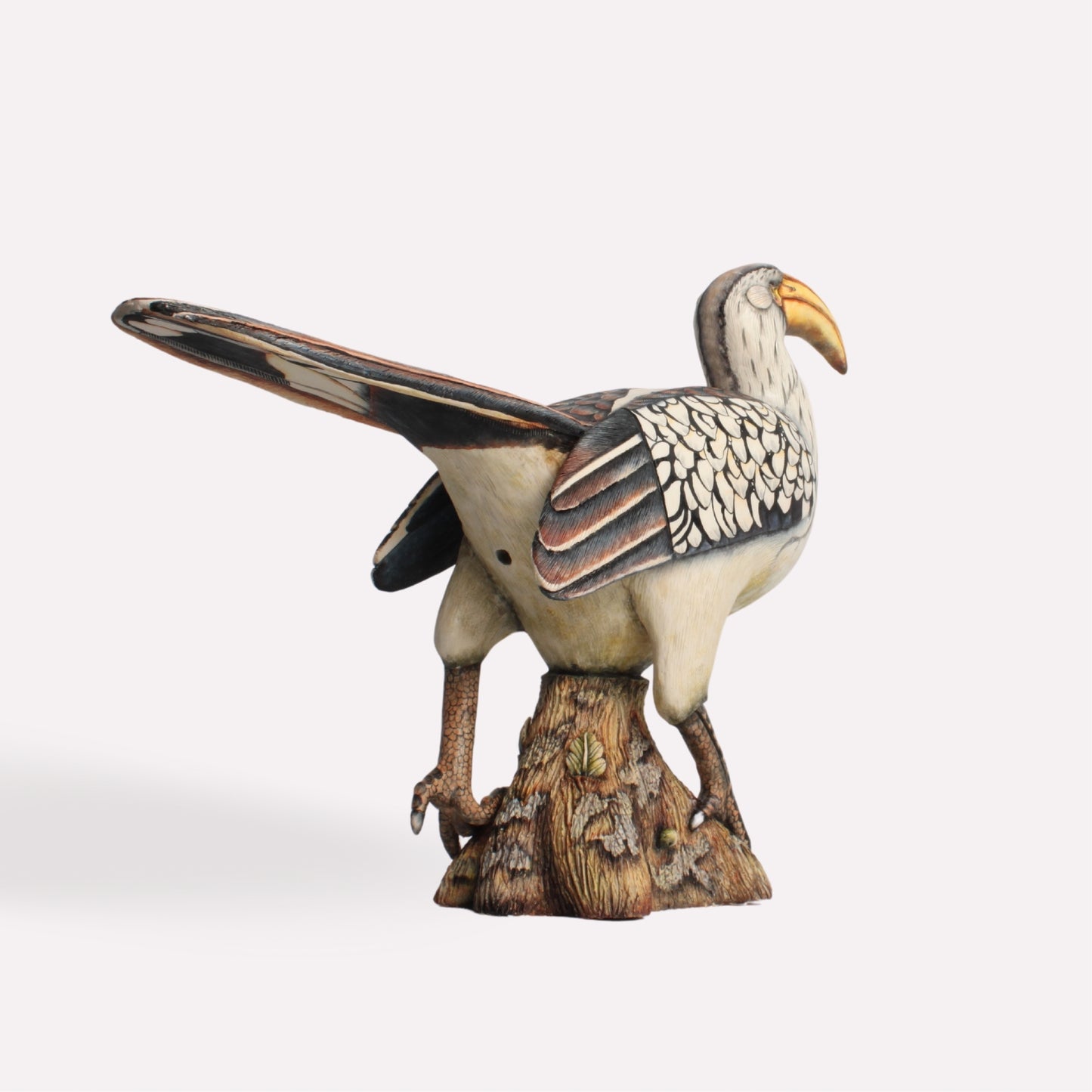 A detailed angle emphasising the elongated tail and the sculpted texture of the base, capturing the dynamic form of the bird in its natural pose.