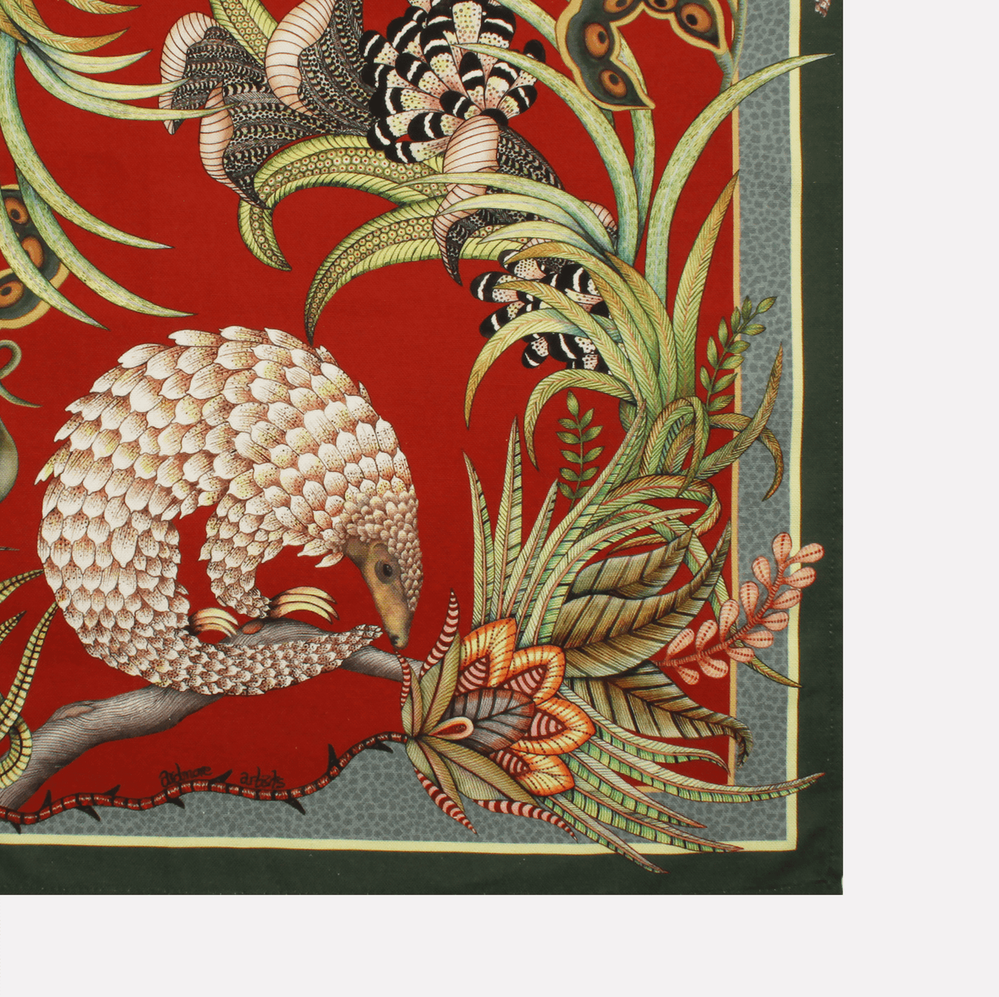 A neatly folded tea towel showcasing a mix of pangolin and plant motifs, accentuated with gold and earthy tones.