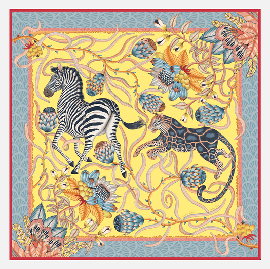 A luxurious oversized silk scarf featuring a vibrant African-inspired design with zebras, leopards, and protea flowers in a bold yellow, blue, and coral palette.