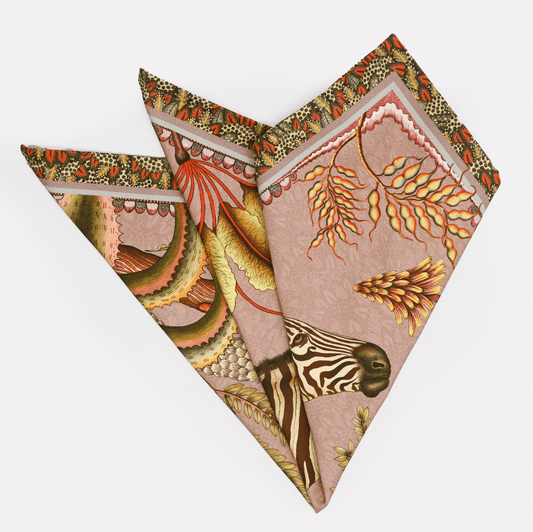 A neatly folded set of Ardmore Thanda Stripe Napkins in Magnolia, showcasing the elegant design with zebras and botanical details in a soft, blush-toned setting.