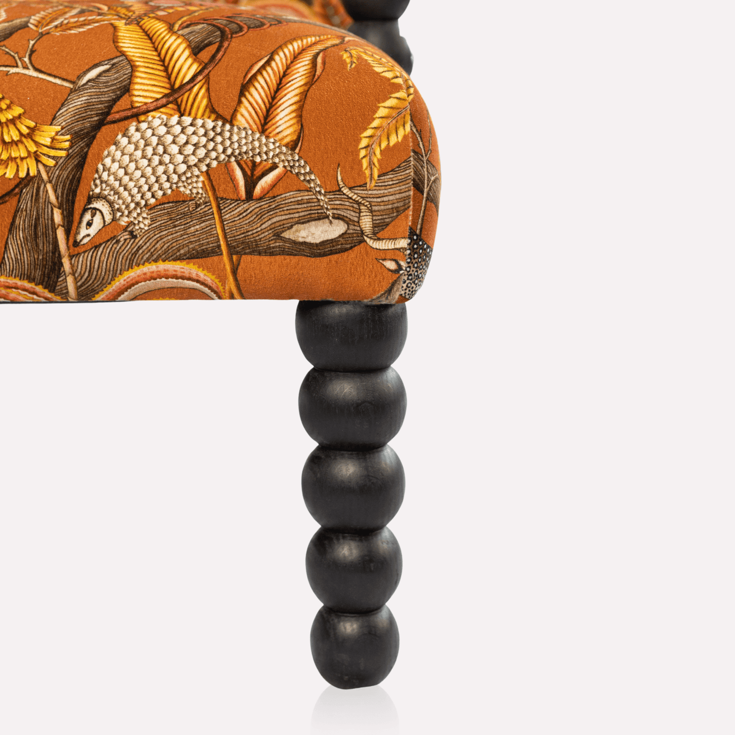 Angled view of the Ardmore Kudu Pod Chair in Pangolin Park Rust Velvet, capturing its elegant structure, deep-seated comfort, and striking fabric design.