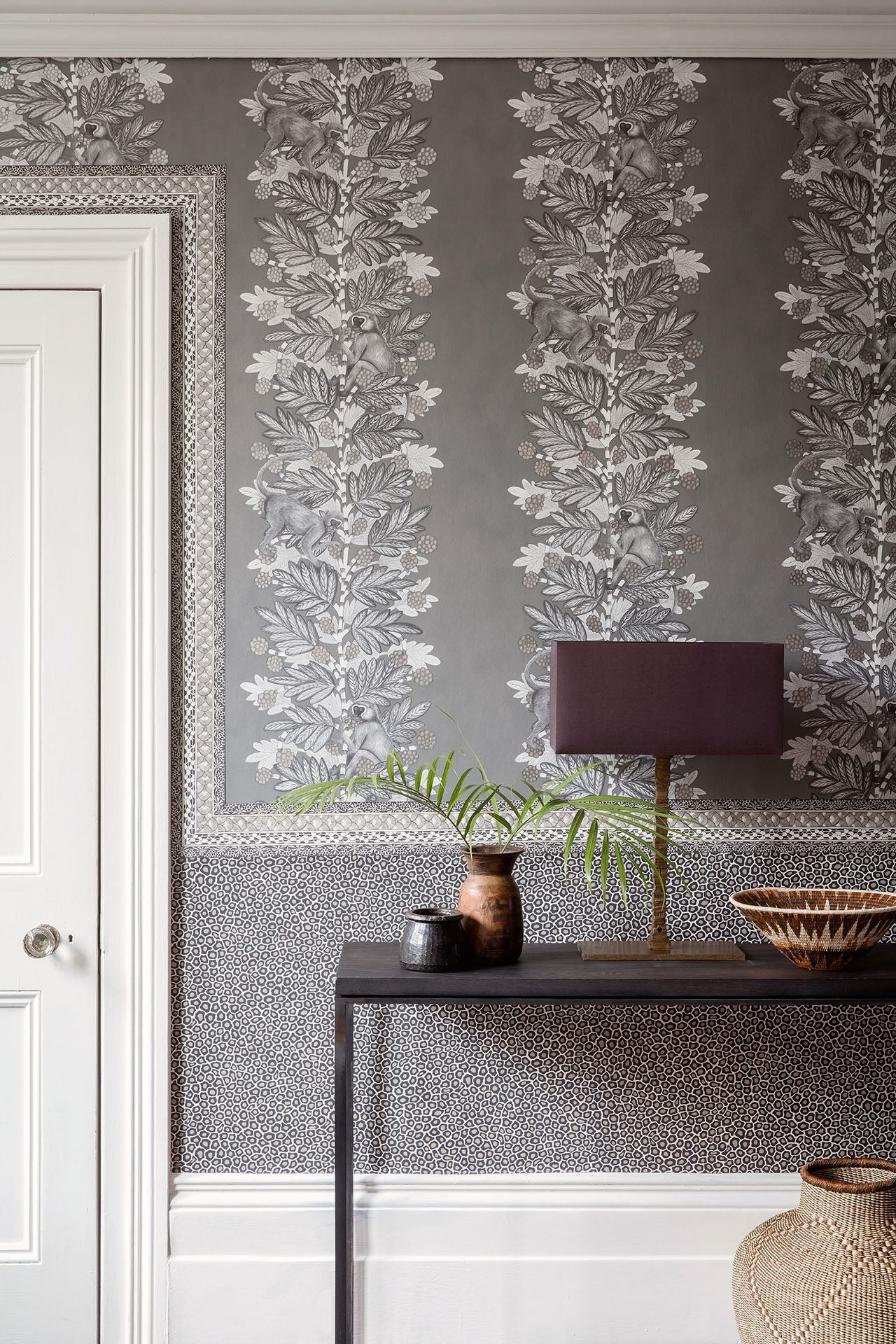 A stylish hallway showcasing the Acacia wallpaper, adding a refined yet whimsical touch with delicate tree and monkey illustrations.