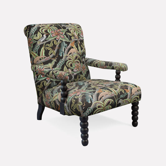 Ardmore Kudu Pod Chair in Pangolin Park Night Linen, upholstered in a rich botanical print with deep green, gold, and earthy tones, featuring a plush seat and elegant black spindle legs.
