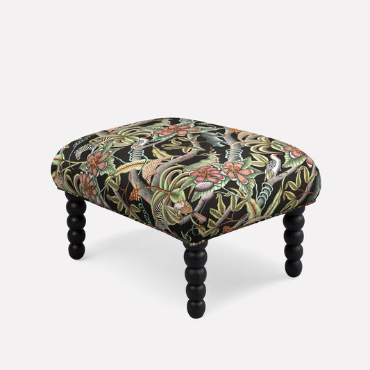 Ardmore Kudu Pod Ottoman in Pangolin Park Night Linen, featuring an intricate dark botanical pattern with black spindle legs, blending African-inspired luxury with contemporary design.