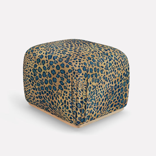 A sophisticated Nyala Ottoman featuring an elegant leopard print fabric in deep midnight blue and golden hues. The ottoman has a rounded, cube-like silhouette with plush upholstery, crafted from a luxurious blend of linen and viscose. The refined design makes it a stylish yet functional statement piece, ideal for interiors seeking a touch of African glamour and contemporary elegance.