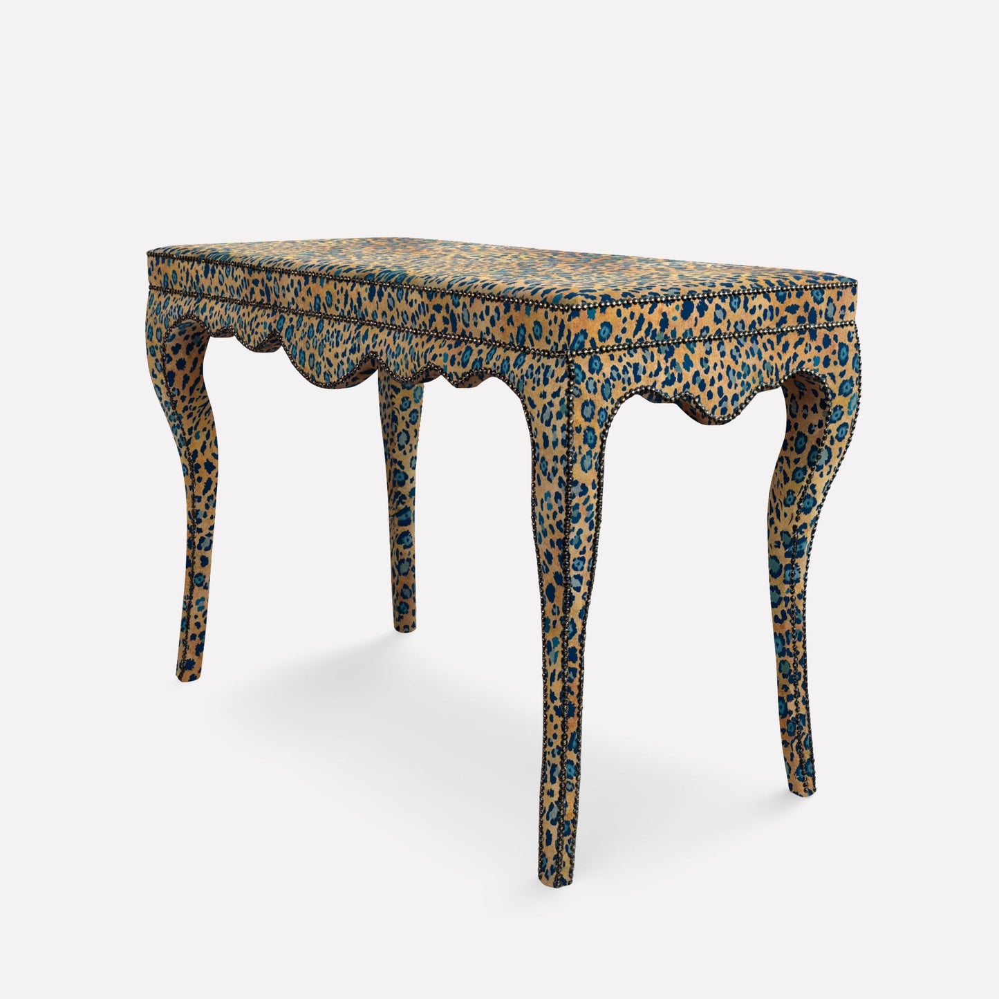 A side-angle view of the Nyala Table, showcasing its sleek glass top, richly textured fabric, and exquisite craftsmanship. The contrasting tones of midnight hues and warm patterns create a bold yet refined centre piece for elegant interiors.