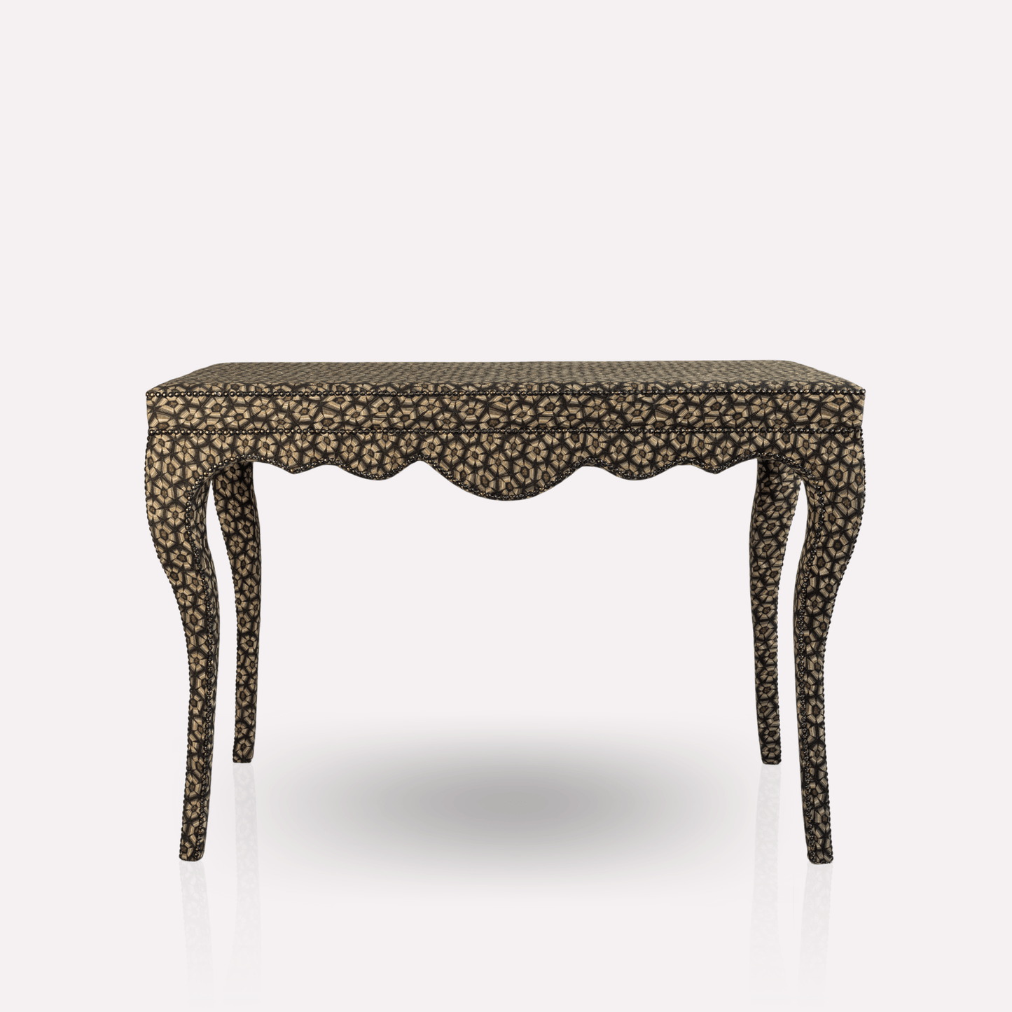 A side view of the Nyala Table, showcasing its sleek glass top and flowing silhouette. The ornate fabric design in silver and charcoal tones enhances its sophisticated elegance.