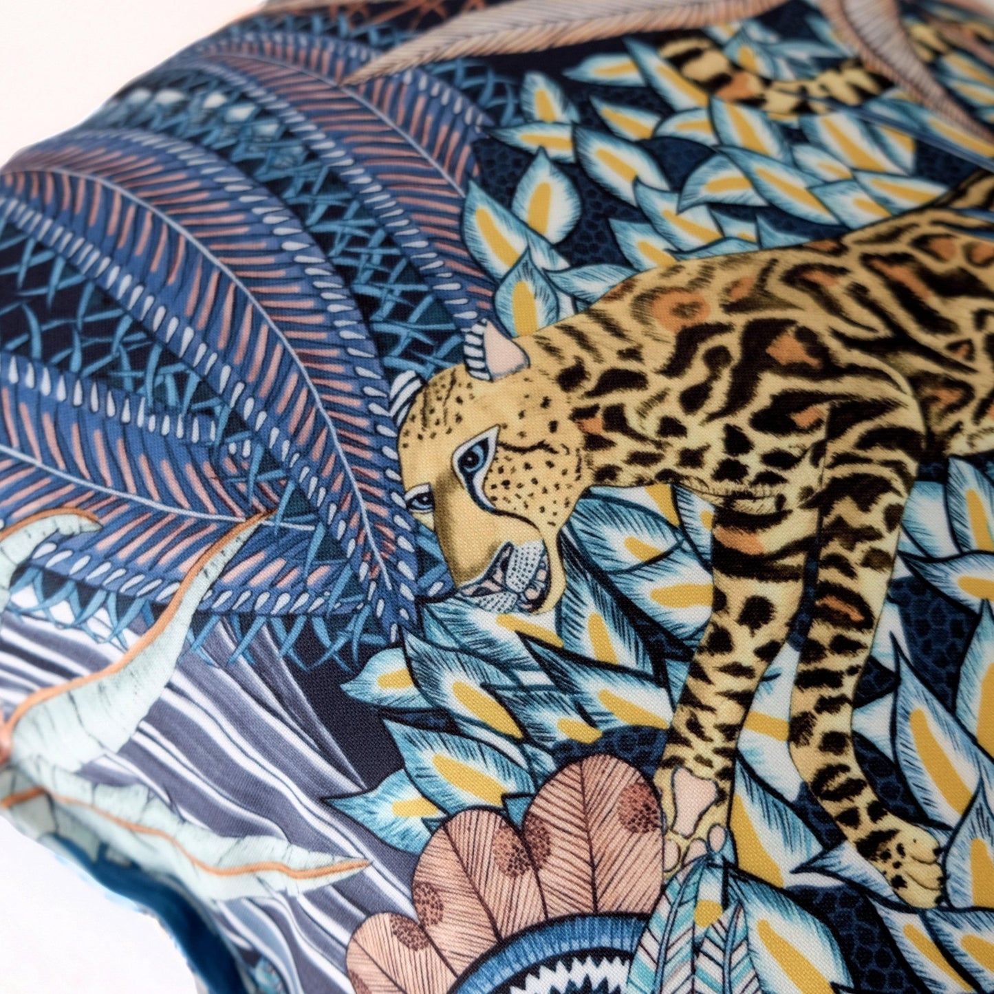 Zoomed-in view of the Sabie Forest Dawn cushion cover, featuring a leopard resting among lush foliage in gold and blue hues.
