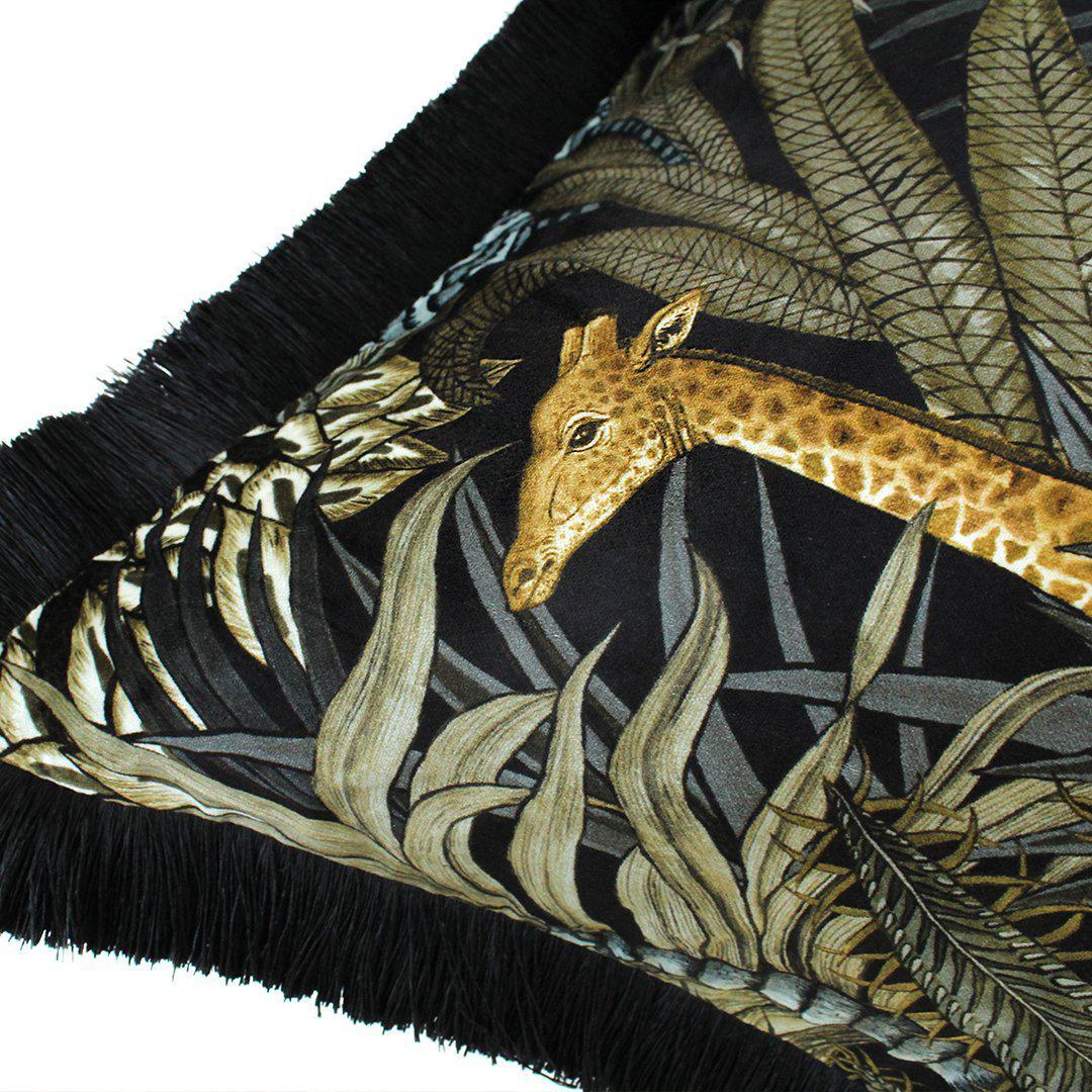 Close-up of the corner of the Sabie Forest Moonlight cushion cover, featuring the head of a giraffe peeking through detailed jungle foliage, with a black fringe edge visible.
