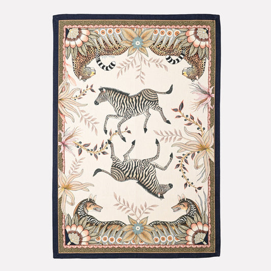 A luxurious tea towel featuring an intricate print of leopards and jackals roaming amidst African-inspired foliage, framed by an elegant patterned border.