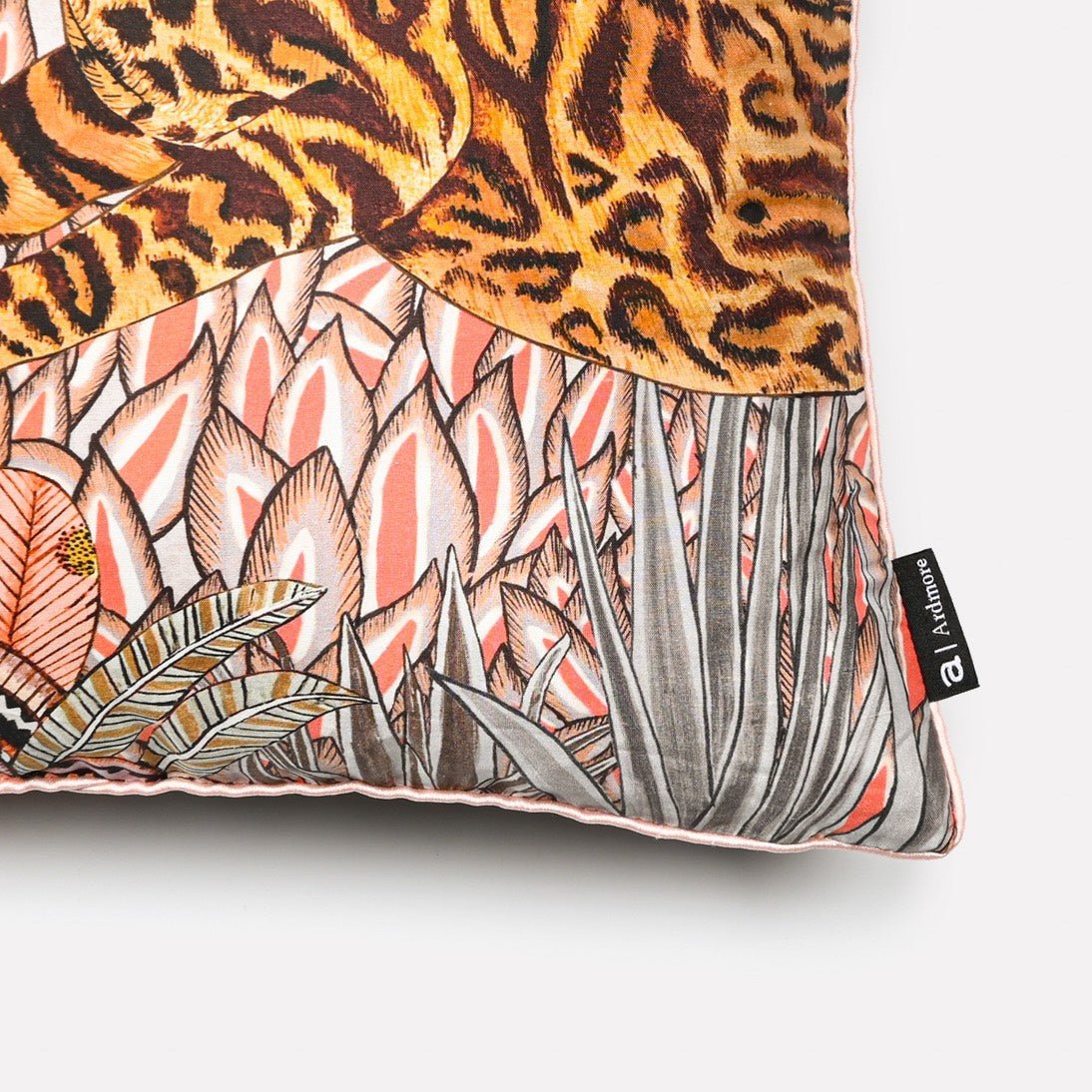 Angled close-up of the Cheetah Kings Forest Magnolia silk cushion cover, highlighting the intricate details of the cheetah and the vibrant magnolia blossoms on luxurious silk fabric.