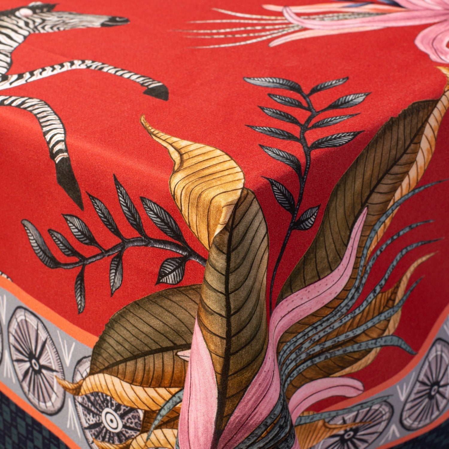 A zoomed-in shot highlighting a folded corner of the tablecloth, revealing exquisite brushwork on the leopards and florals.