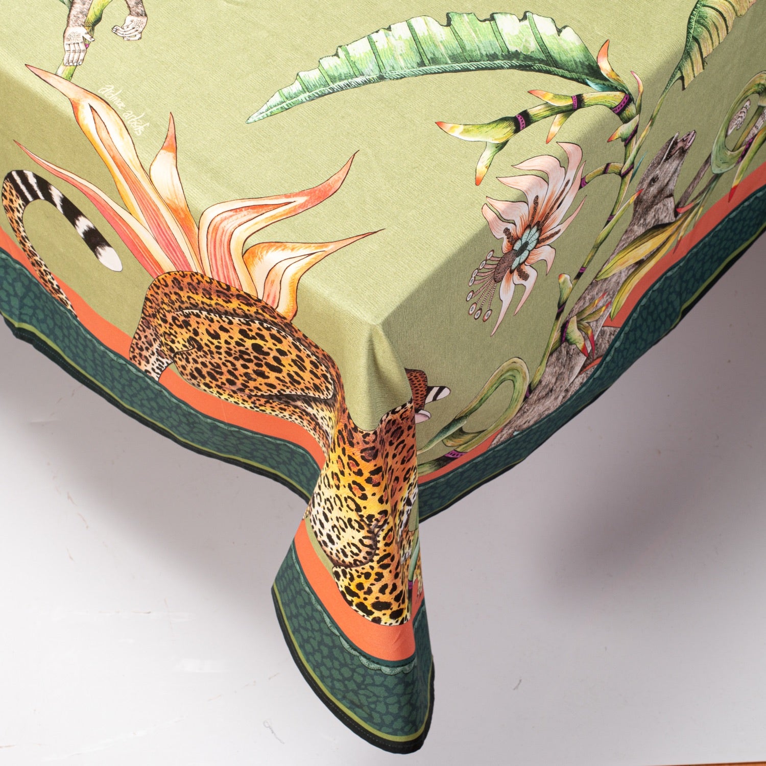 A side view of the tablecloth hanging over the edge of a table, displaying its intricate border and patterns.