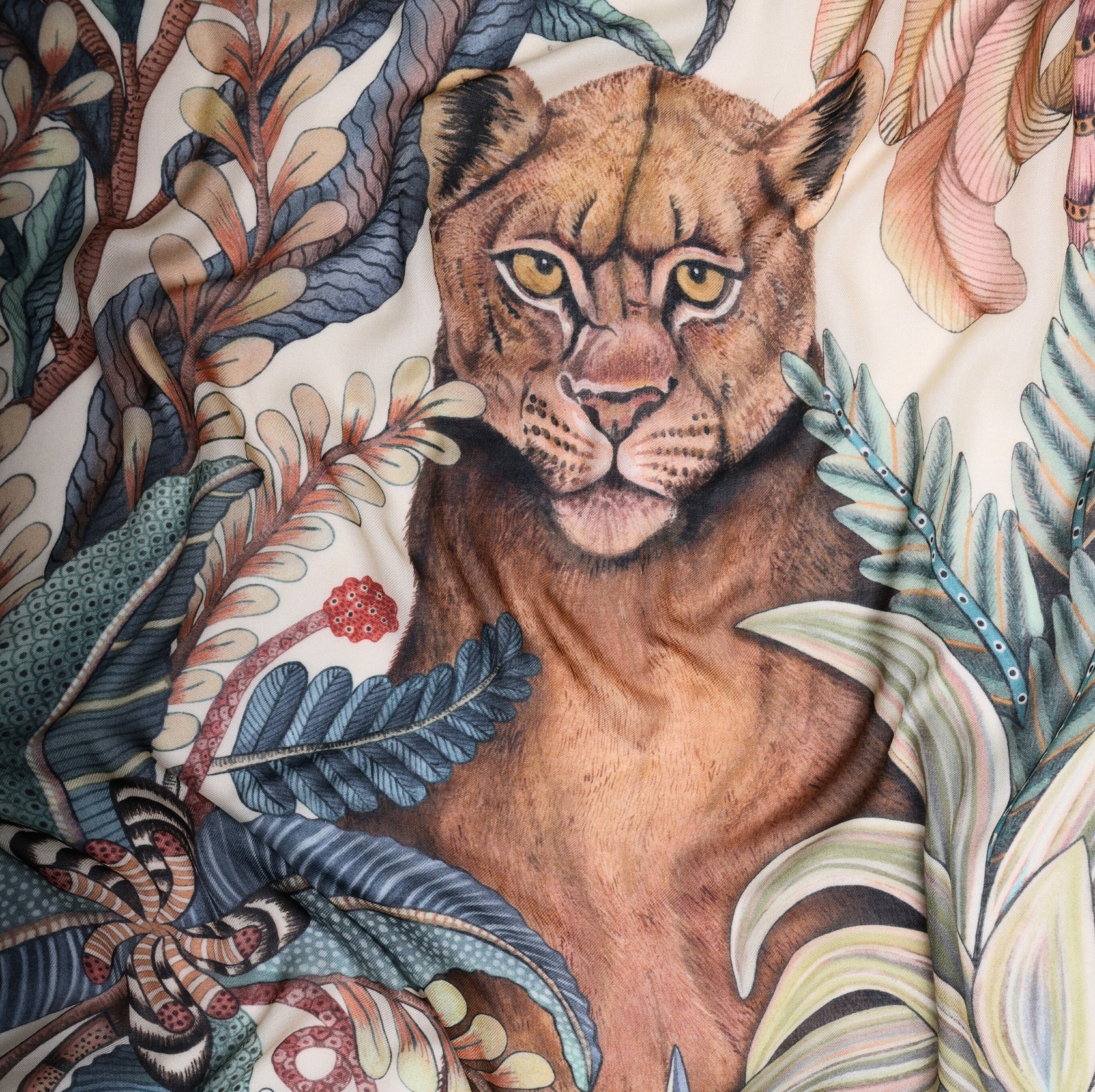 A detailed section highlighting the expressive face of a lioness, framed by jungle leaves, emphasising the scarf’s artistic craftsmanship.