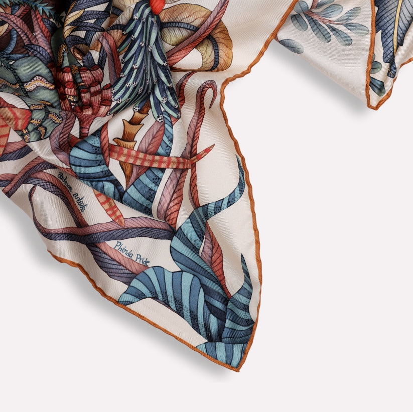 A macro shot capturing the hand-rolled edges of the silk scarf, emphasising craftsmanship, softness, and vibrant colour contrast.