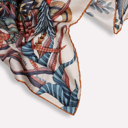 A macro shot capturing the hand-rolled edges of the silk scarf, emphasising craftsmanship, softness, and vibrant colour contrast.