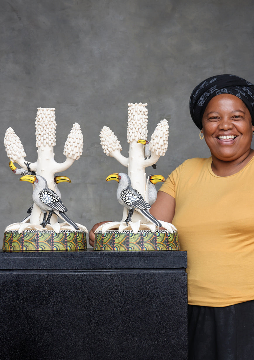 A photograph of an artist proudly presenting the finished candle holders, showcasing their scale and craftsmanship.