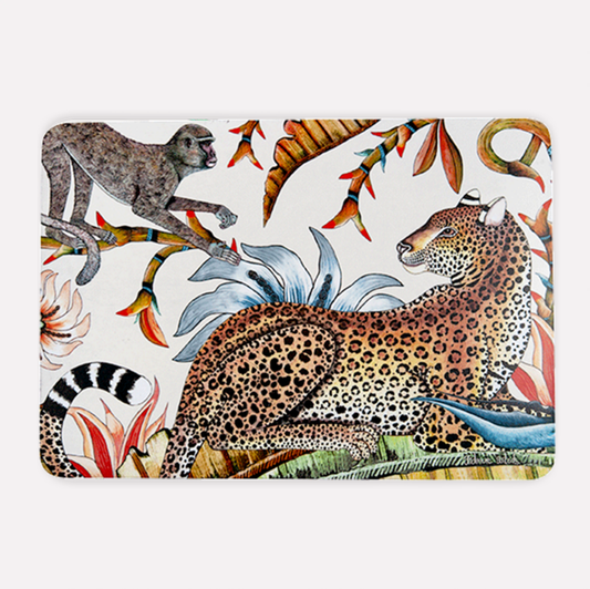 A hardboard placemat featuring an elegant design of a resting leopard with golden fur and intricate rosettes, surrounded by lush tropical foliage, a playful monkey, and vibrant Lucky Bean flowers against a warm sandstone background.