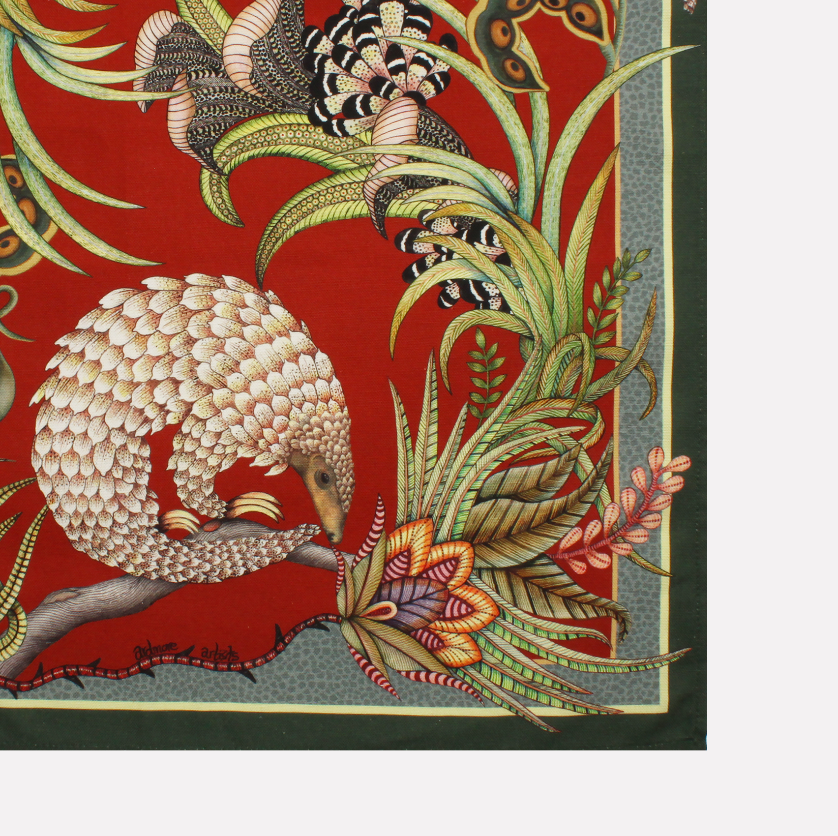 A neatly folded tea towel showcasing a mix of pangolin and plant motifs, accentuated with gold and earthy tones.
