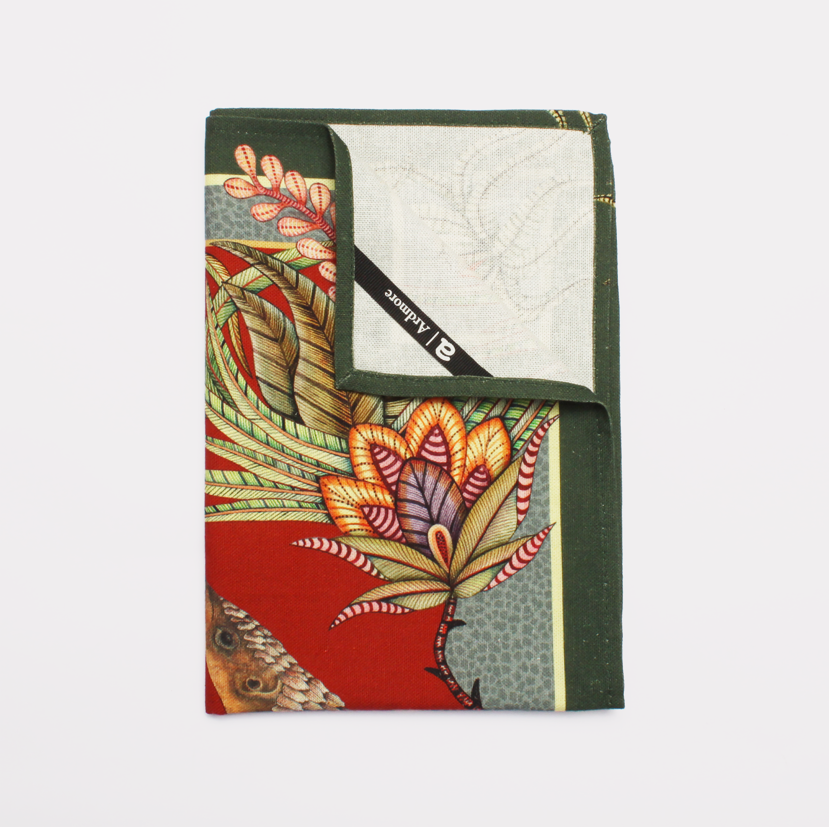 A close-up of stacked tea towels displaying detailed pangolin illustrations intertwined with lush foliage and floral patterns.