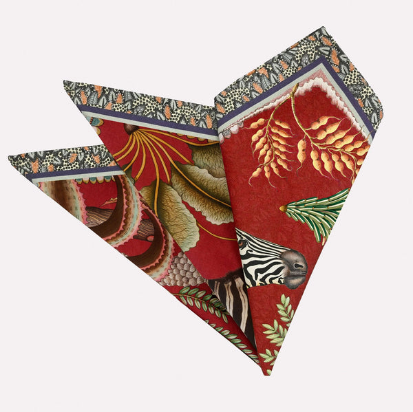 A neatly folded pair of Ardmore Thanda Stripe Napkins in Royal Red, showcasing the intricate African-inspired design with bold red tones, zebra, and floral motifs.