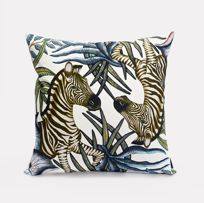 Front view of the Thanda Stripe Tanzanite Cotton Cushion Cover, showcasing a majestic zebra design surrounded by lush African flora on a soft white background, made from 100% cotton.