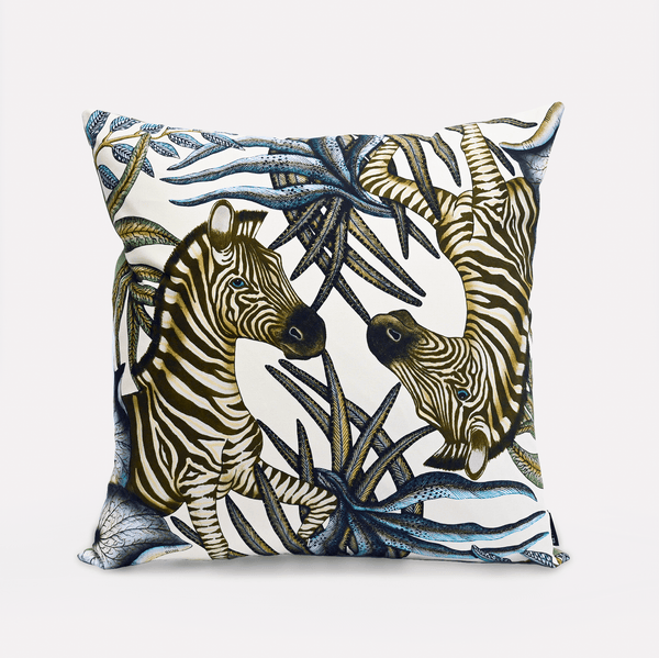 Front view of the Thanda Stripe Tanzanite Cotton Cushion Cover, showcasing a majestic zebra design surrounded by lush African flora on a soft white background, made from 100% cotton.