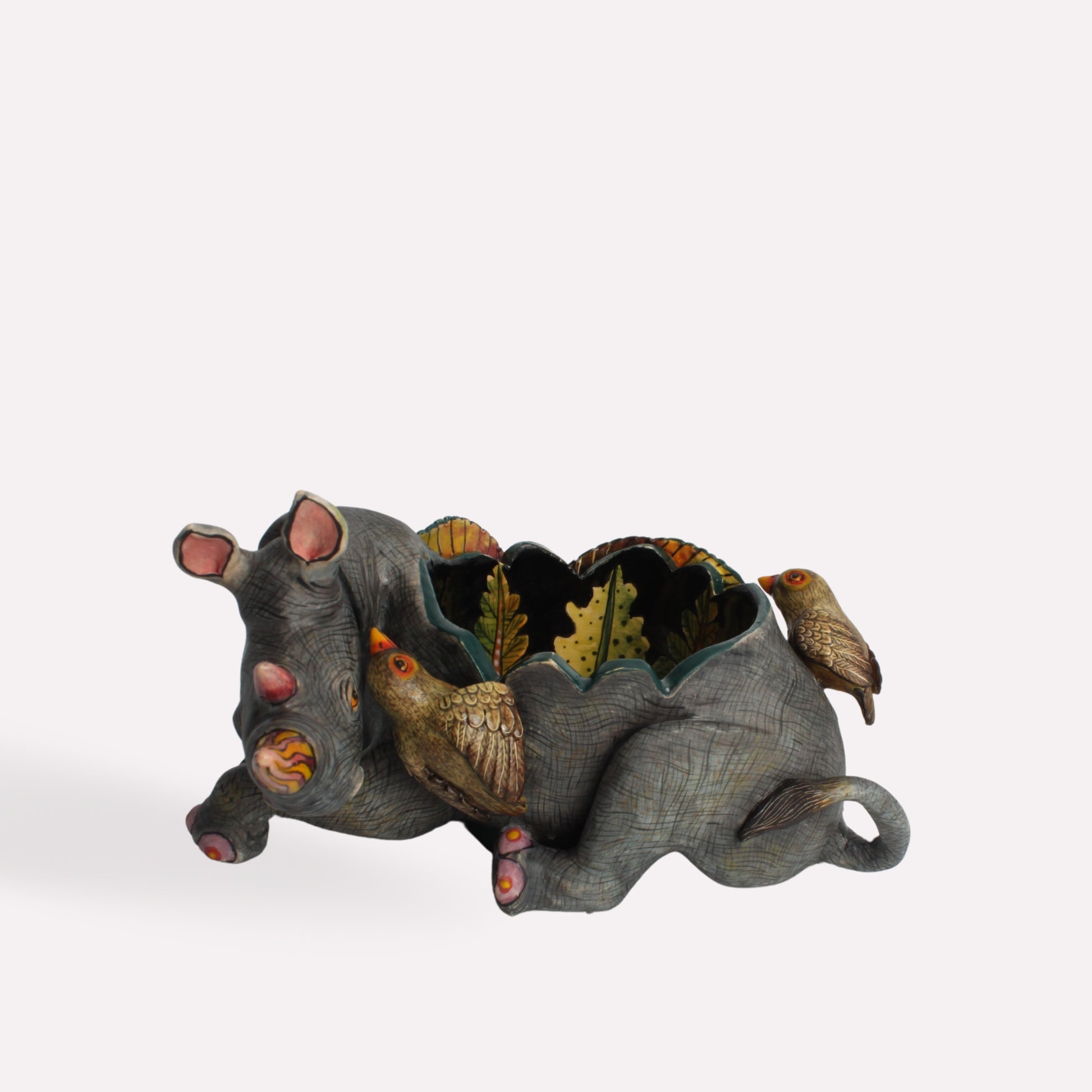 A side-angle shot capturing the bowl’s three-dimensional sculptural details, highlighting the craftsmanship in both the rhino’s anatomy and the decorative foliage.
