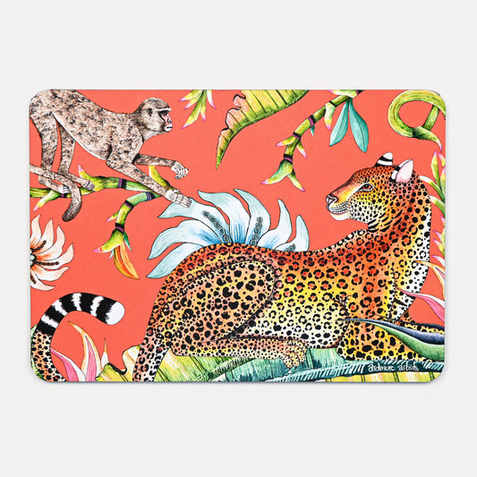A vibrant hardboard placemat featuring a golden leopard lounging among tropical foliage, with a monkey playfully perched above, set against a bold coral background.