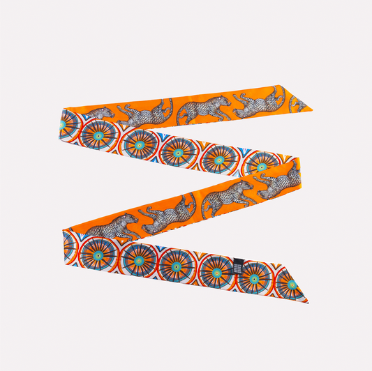 A vibrant, elongated silk twill in bold flame orange, adorned with intricate African Amasumpa patterns and elegant leopards.