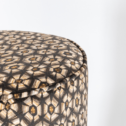 A closer look at the pouffe’s upholstery, showing the detailed craftsmanship and the contrast between the silver-patterned velvet and the brass base.