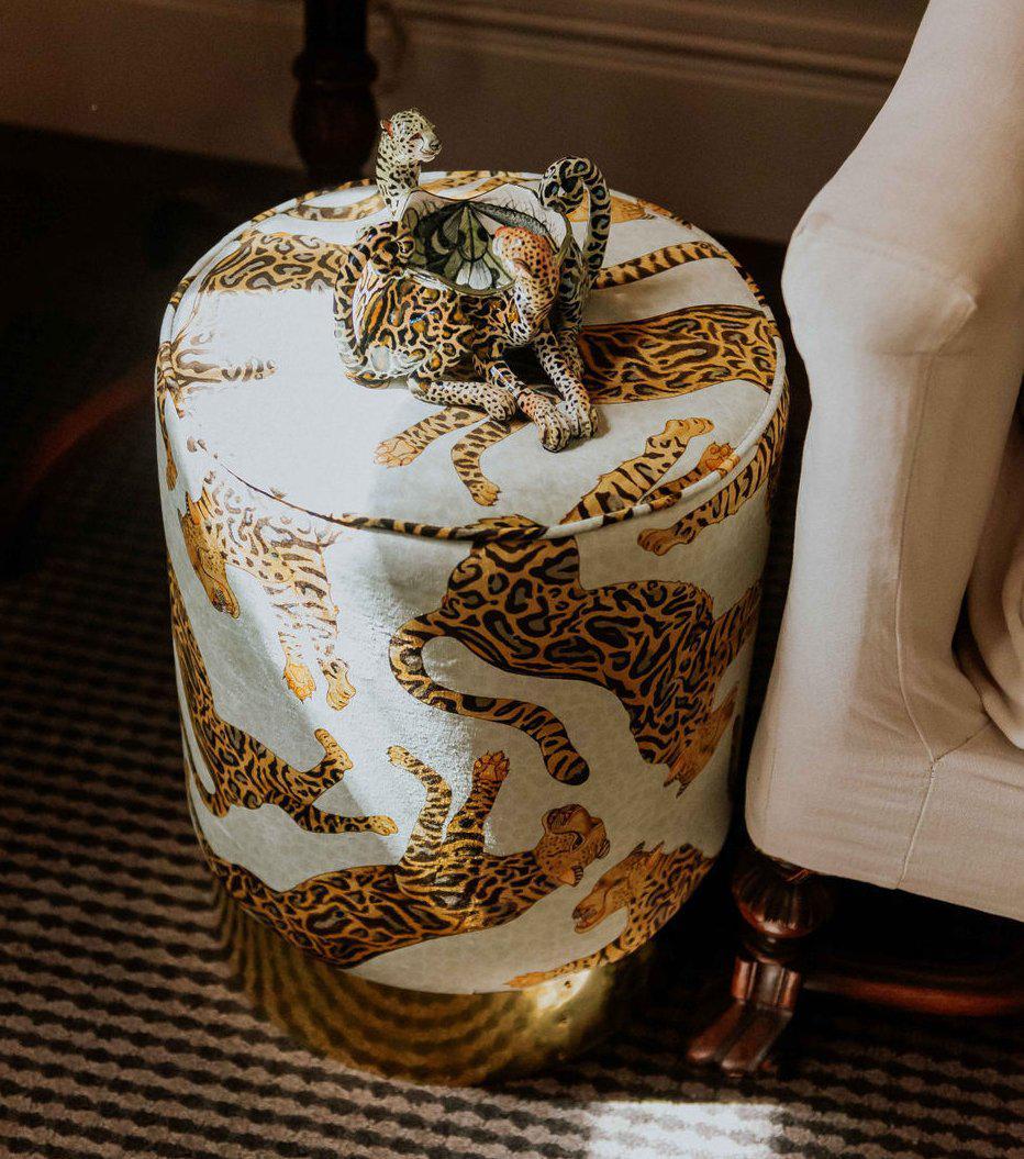 Angled perspective of the Ardmore Cheetah Kings Stone Velvet Pouffe, revealing its plush design, intricate patterns, and lustrous brass base that adds a timeless touch to any space.