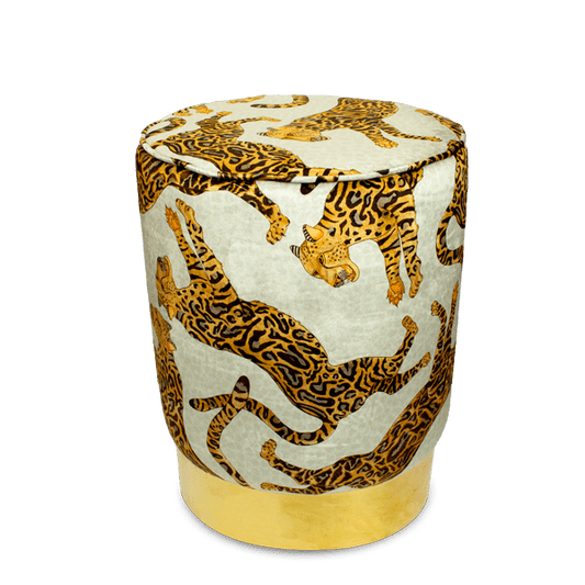 Elegant velvet pouffe adorned with Ardmore's Cheetah Kings Stone design, showcasing intricate cheetah motifs in rich golden hues against a stone-coloured background, set on a gleaming brass base.