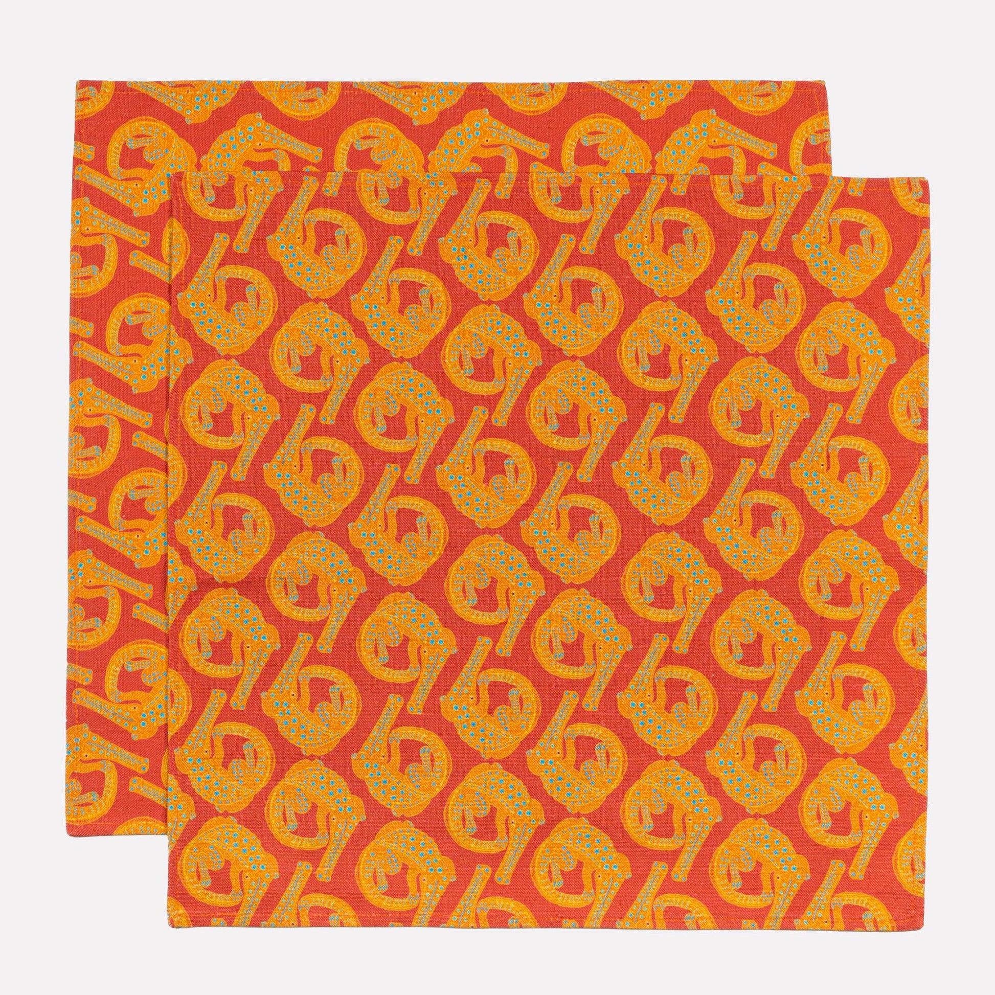 A close-up of the Ardmore Croco napkin in Sunset, displaying a zoomed-in view of the crocodile pattern with deep orange and golden-yellow hues on the fabric.