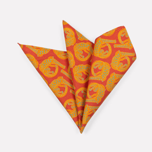 A pair of Ardmore Croco napkins in Sunset, elegantly folded into a fan shape to highlight the bold reptilian motif and rich sunset-toned fabric.