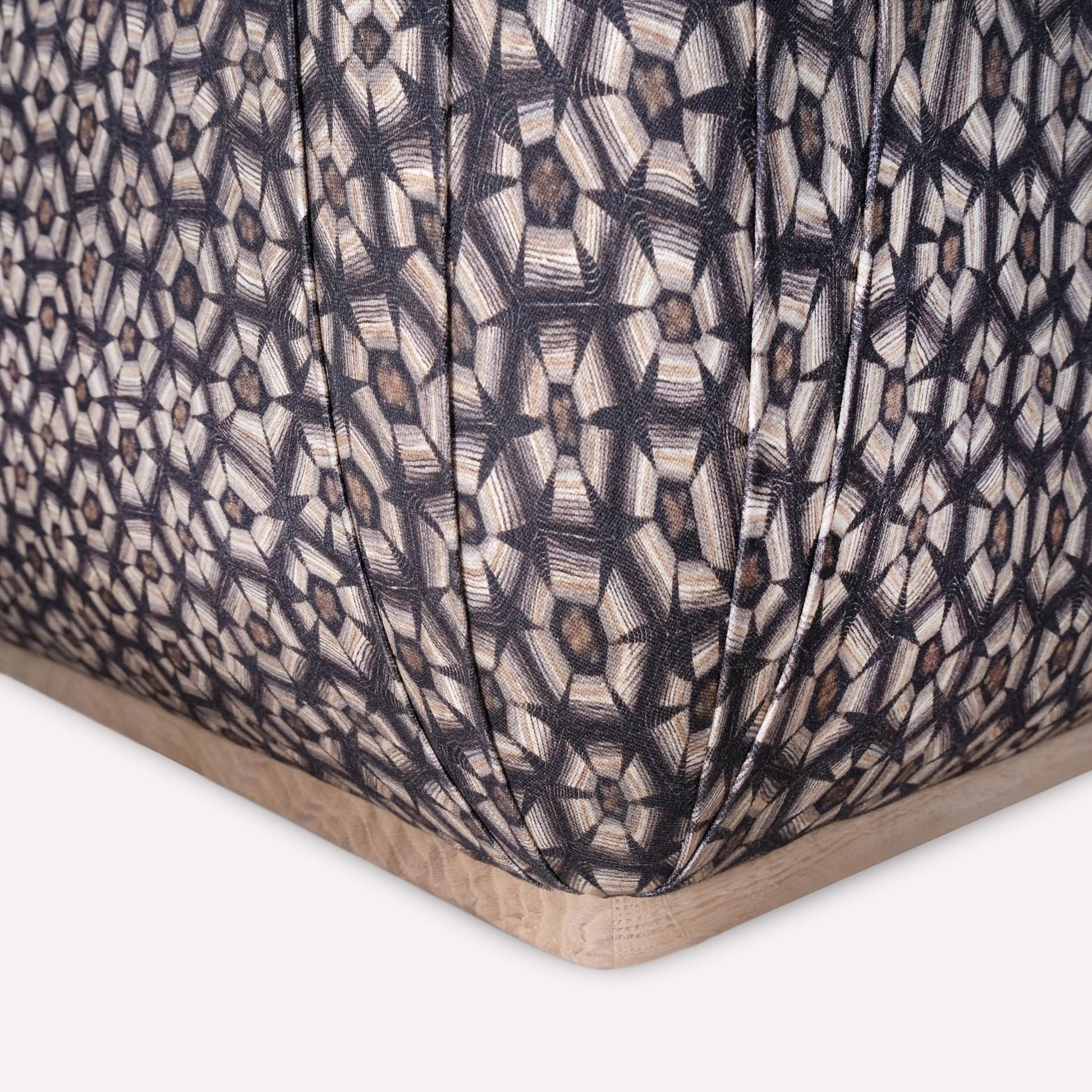 A close-up of the ottoman’s fabric texture, highlighting the detailed tortoise-shell pattern and subtle sheen of the linen blend, emphasising its intricate craftsmanship and high-end appeal.