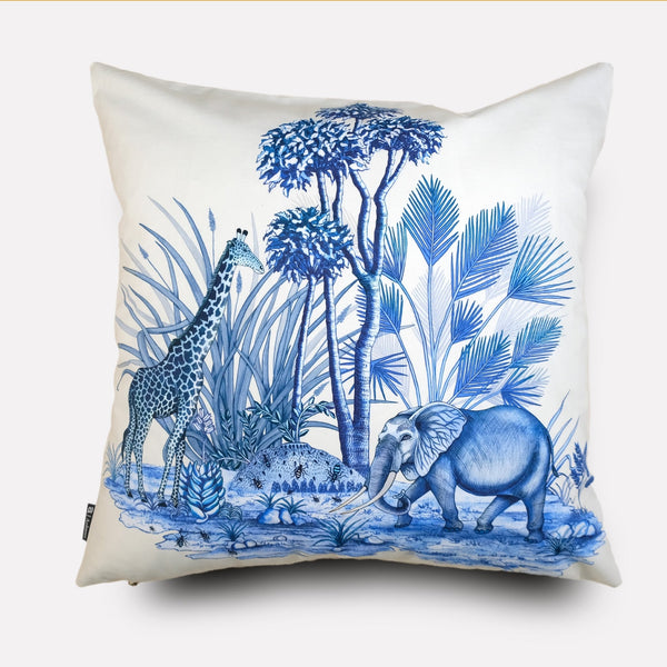 A square cushion cover with a crisp white background, featuring an intricate blue wildlife design showcasing an elephant, a giraffe, and lush African flora.