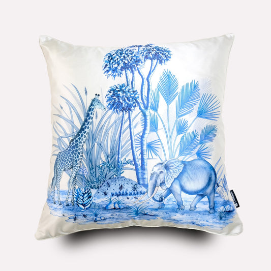 A white silk cushion cover featuring an intricate blue wildlife illustration, including elephants, giraffes, and African flora, inspired by Tanzanite hues.