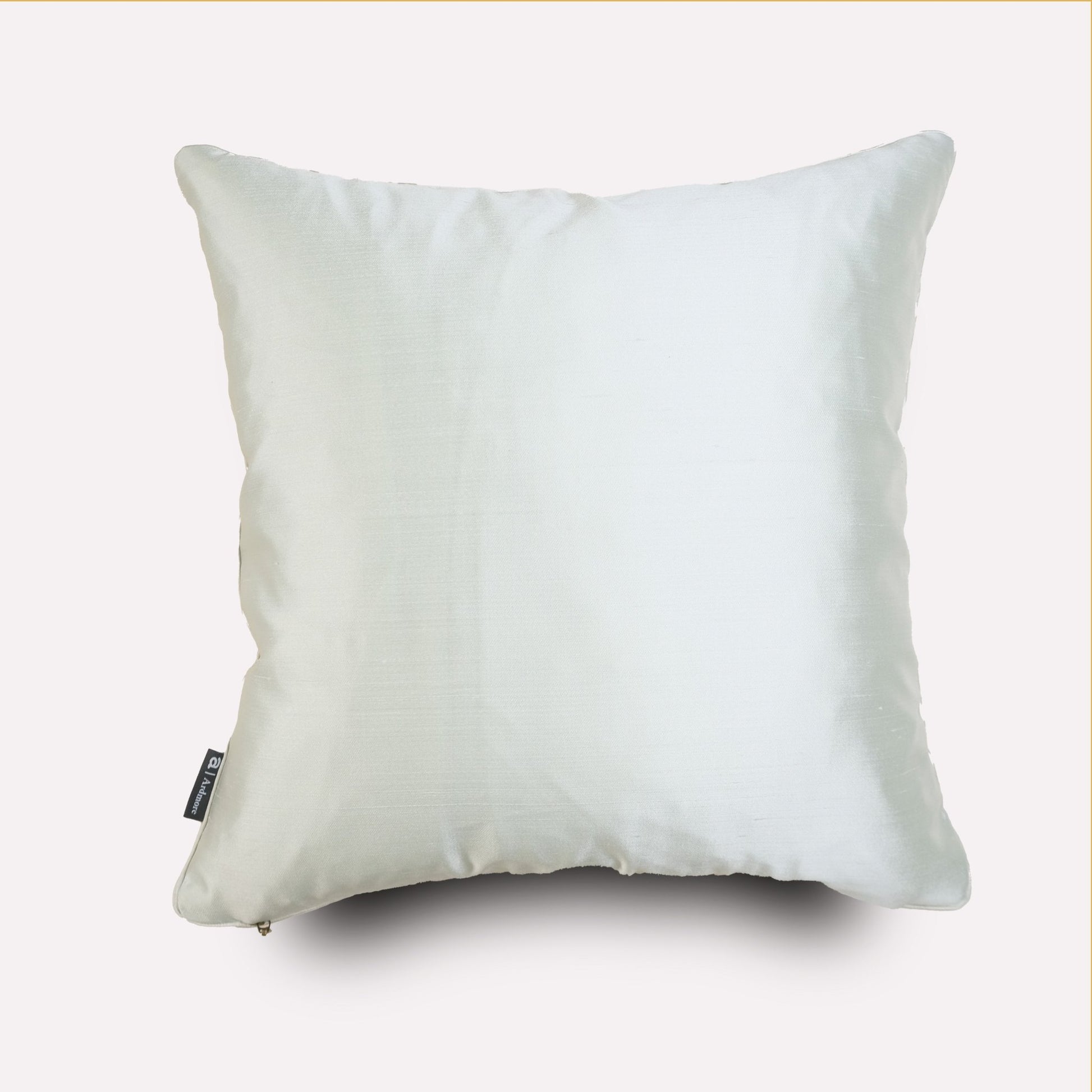 The reverse side of the cushion, showcasing a plain white silk fabric with smooth texture and elegant piping.