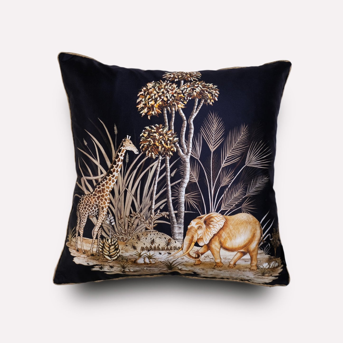 A luxurious black silk cushion cover featuring an intricate wildlife illustration with elephants, giraffes, and African flora in golden hues.