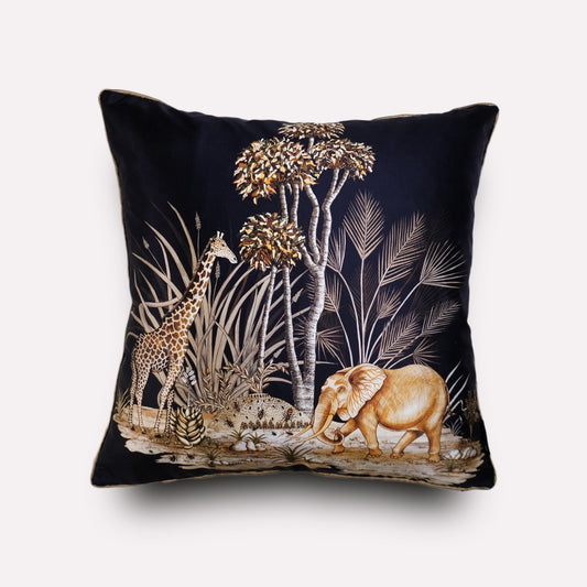 A luxurious black silk cushion cover featuring an intricate wildlife illustration with elephants, giraffes, and African flora in golden hues.