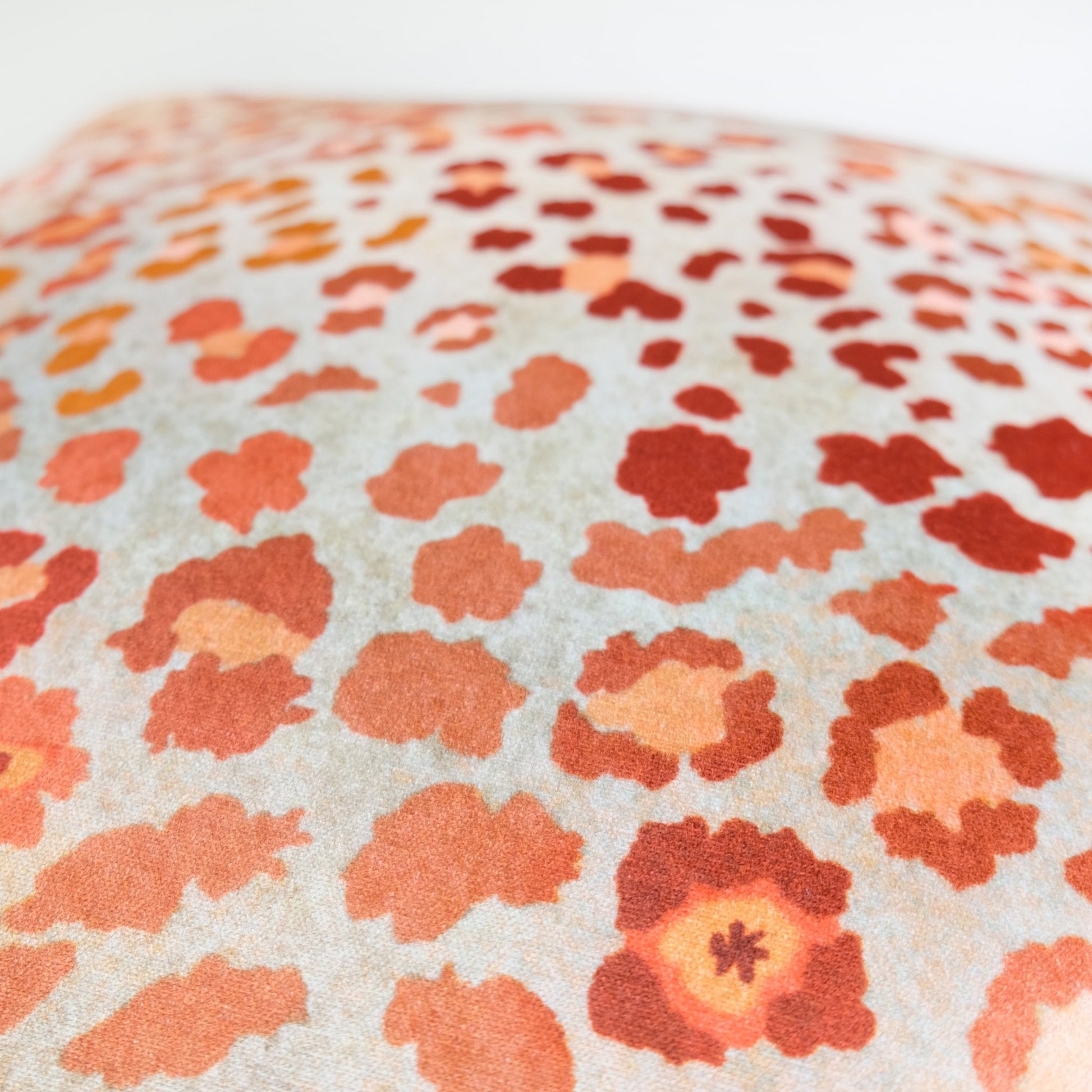 Angled view of the Safari Spot Coral Velvet Cushion Cover, highlighting the soft texture and bold, colourful pattern.