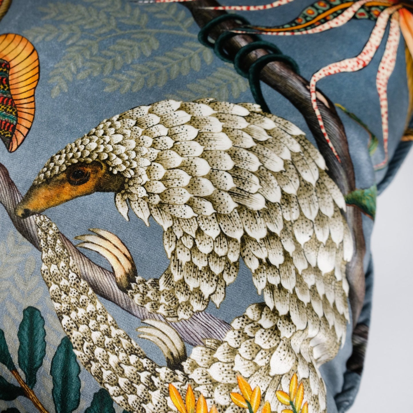 Close-up view of the Thanda Pangolin Park Ash Velvet Cushion Cover, focusing on the detailed pangolin artwork and textured design elements.