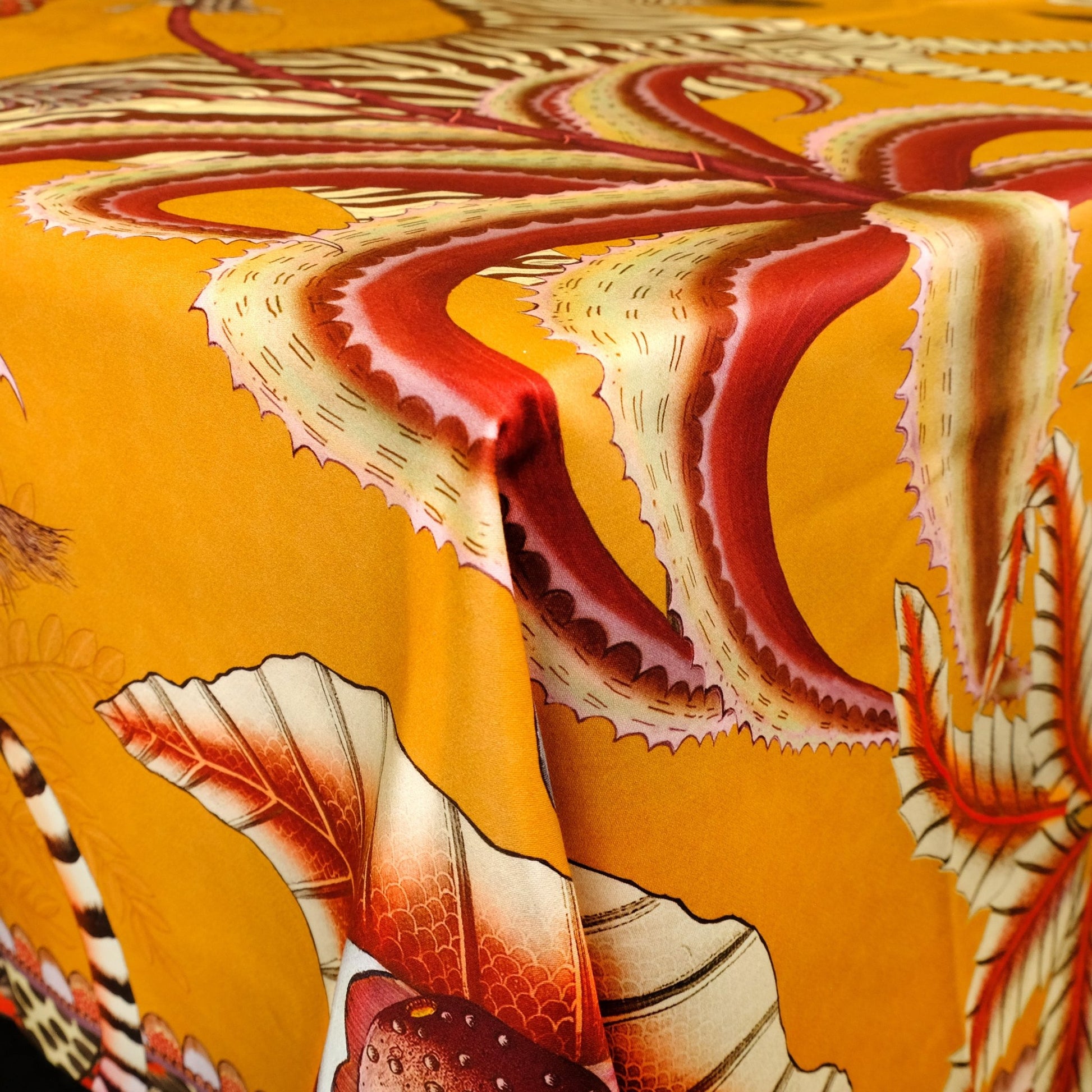 A detailed shot showcasing the tablecloth elegantly draping over the table’s edge, revealing flowing patterns of foliage and wildlife.