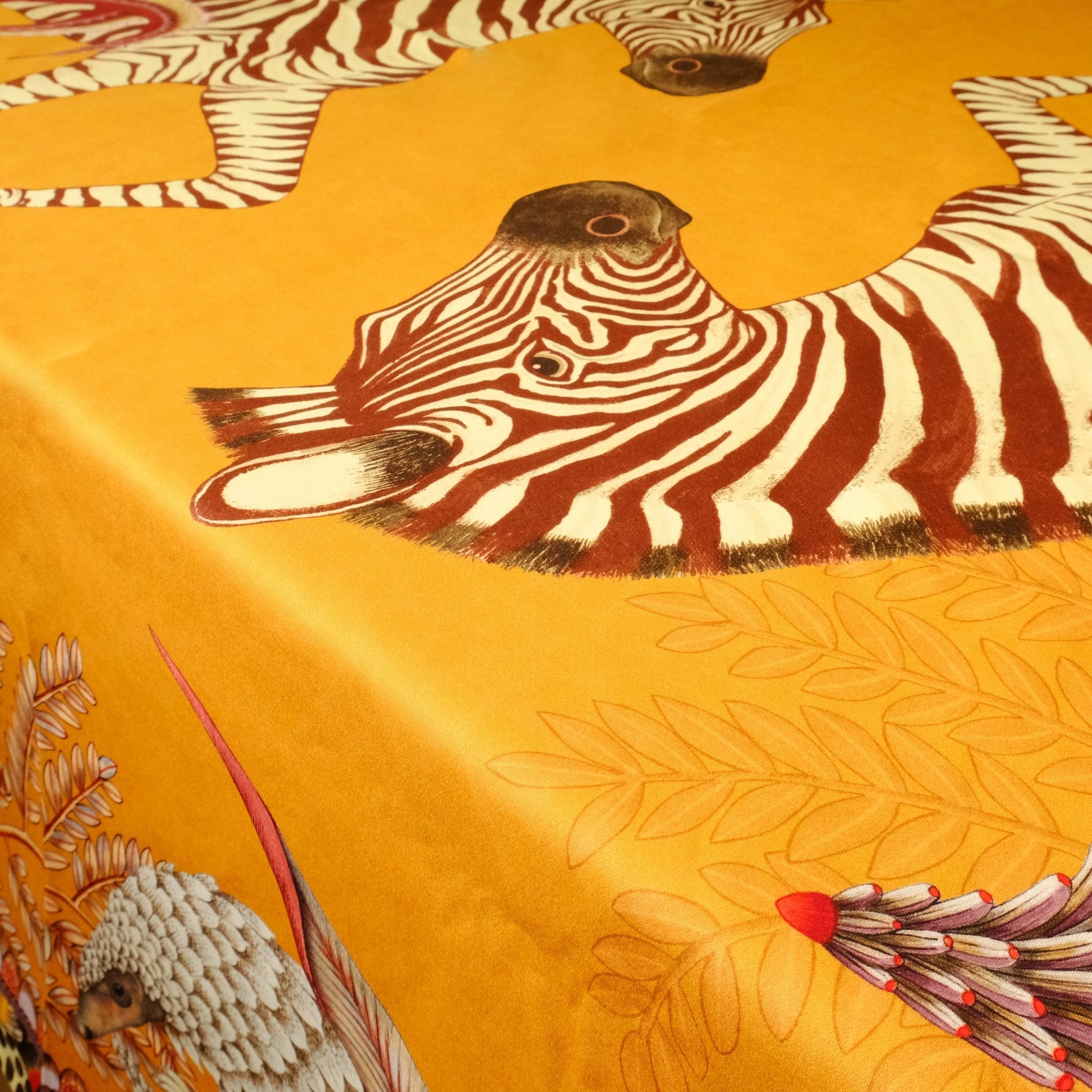 A close-up of a zebra illustration against the vibrant orange fabric, highlighting the fine artistry and intricate design.