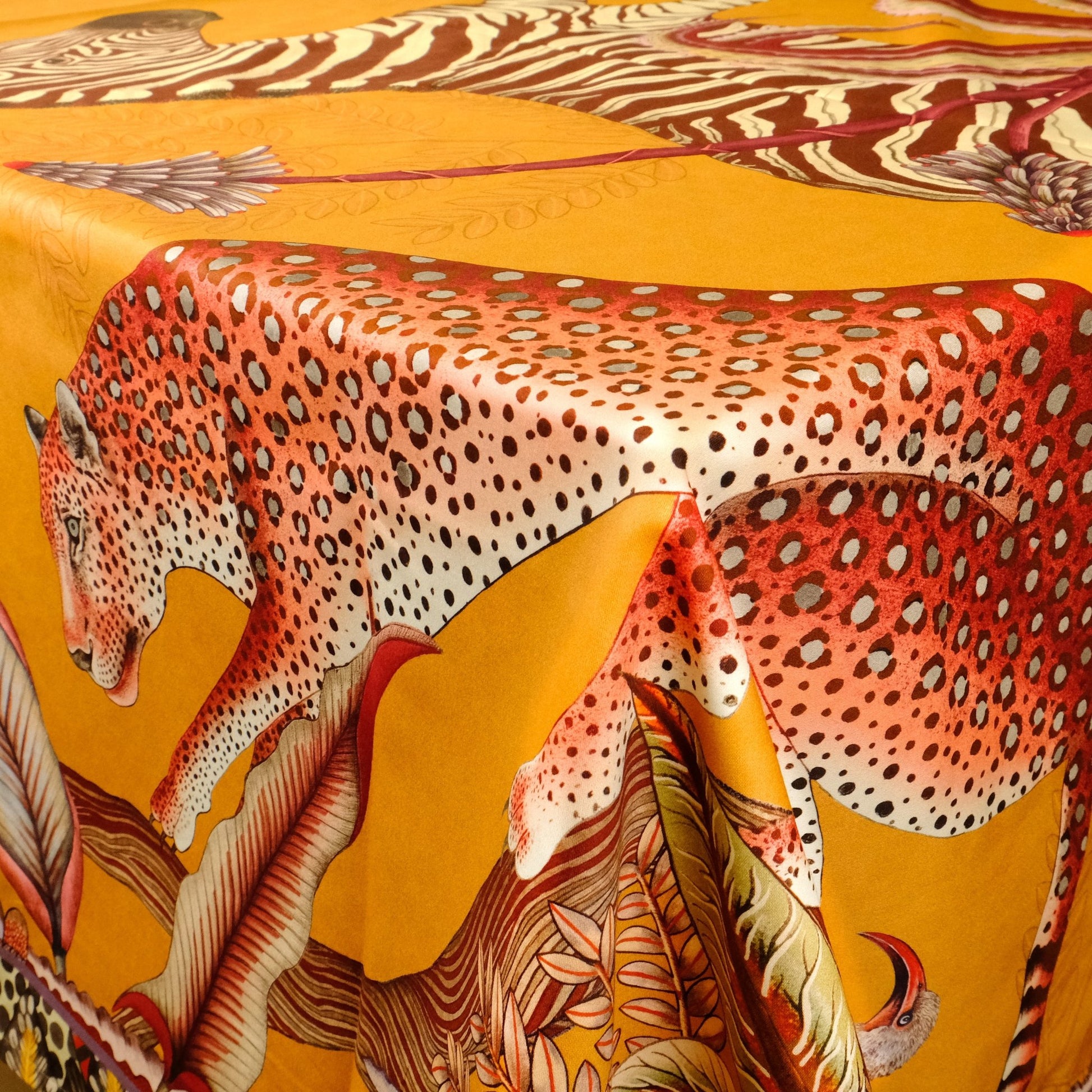 A zoomed-in shot of a leopard gracefully resting among painted aloes and floral elements, capturing the richness of the print.
